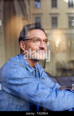 Portrait of man wearing glasses behind windowpane Stock Photo