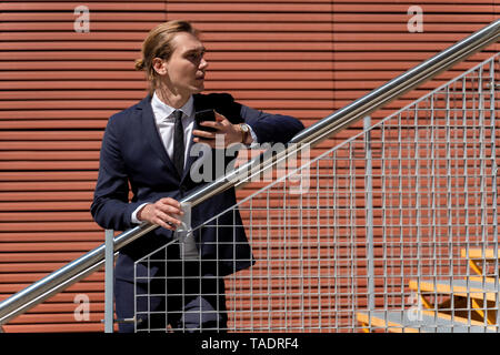 Young businessman holding smartphone and takeaway coffee outdoor Stock Photo