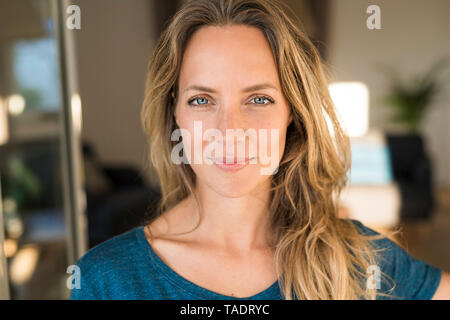 Portrait of smiling blond woman at home Stock Photo