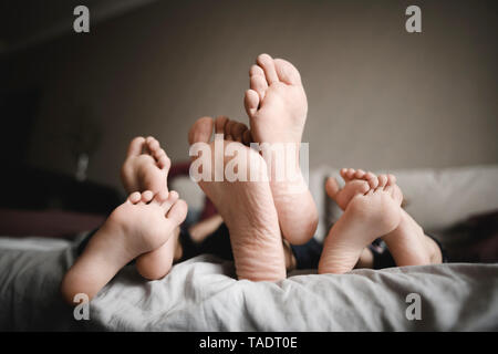 Feet of father and his children relaxing together at home Stock Photo