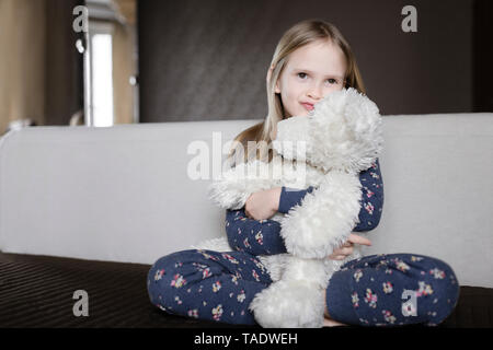 Portrait of smiling little girl wearing pyjama with floral design holding white teddy bear