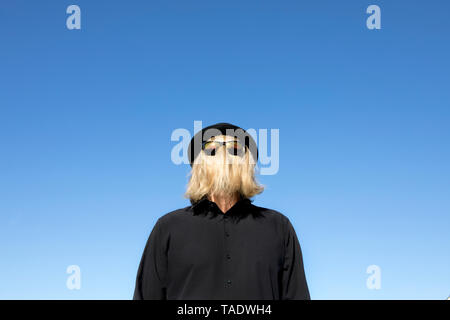 Blond hair covering man's face wearing sunglasses and bowler hat Stock Photo