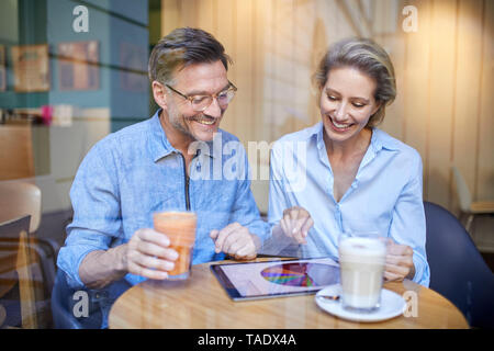 Happy woman and man using tablet in a cafe Stock Photo