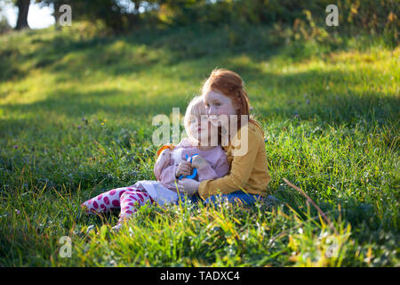 Two sisters cuddling in field Stock Photo