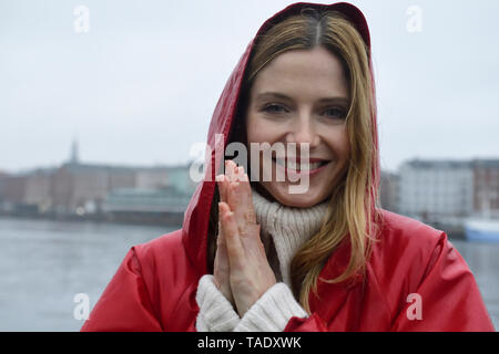 Denmark, Copenhagen, portrait of happy woman at the waterfront in rainy weather Stock Photo