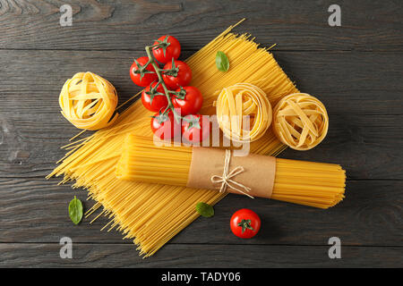 Composition with pasta, tomatoes and basil on wooden background, space for text and top view Stock Photo
