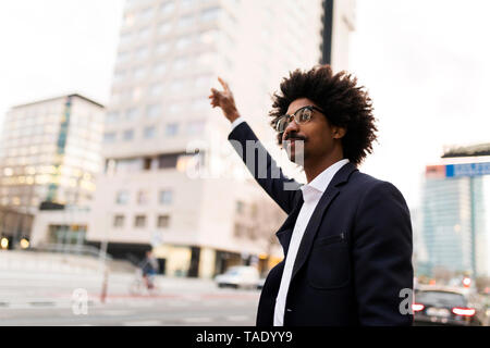 Spain, Barcelona, businessman standing at a street in the city hailing a taxi Stock Photo
