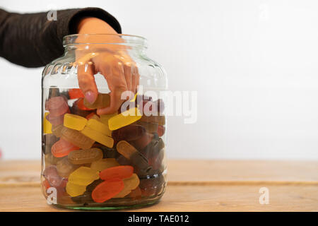 hand of child in candy jar. Grabbing candy out of the jar, white background with Copy space Stock Photo