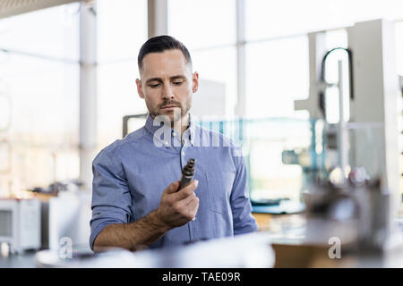 Businessman examining workpiece in factory Stock Photo
