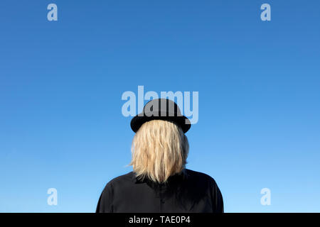 Blond hair covering man's face wearing bowler hat Stock Photo