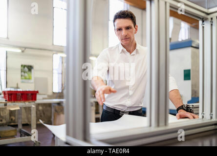 Man wearing white shirt in factory thinking Stock Photo