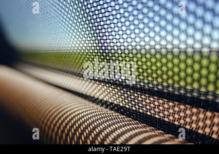Sun blinds on the glass of the rear door of the car black color close-up protects the textured grid from the sun's rays. Car service. Stock Photo