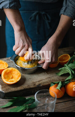 Young man's hands squeezing orange Stock Photo