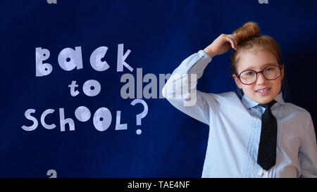 Back to school horizontal banner. Elementary grade schoolgirl in spectacles. Chalk style lettering with question mark. Confused student scratching hea Stock Photo