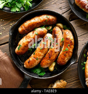 Close up of grilled sausages in frying pan over wooden background. Top view, flat lay Stock Photo