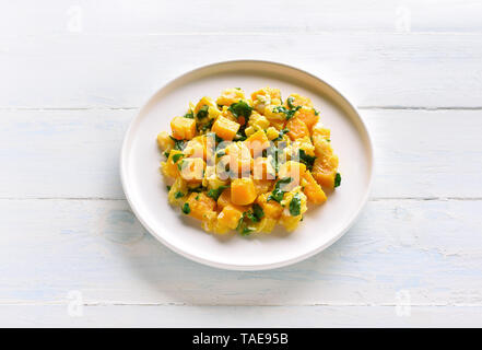 Stir-fried pumpkin with eggs on plate over white wooden background. Pumpkin and egg stir fry in thai style. Stock Photo
