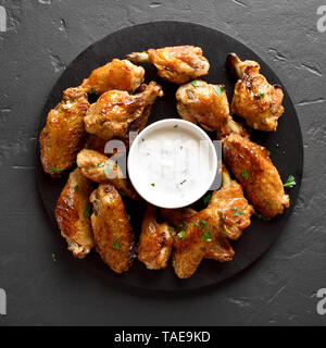 Roasted chicken wings with sauce on black stone background. Top view, flat lay Stock Photo