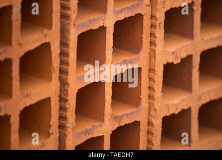Macro of red hollow blocks arranged side by side. Interesting construction texture or background with copy space. Stock Photo