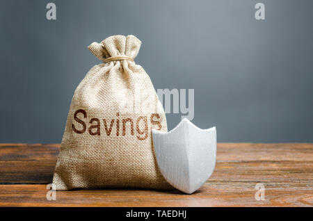 Bag with the words Savings and protection shield. Concept of protection of savings and cash, guaranteed deposits. Compensation for losses in inflation Stock Photo