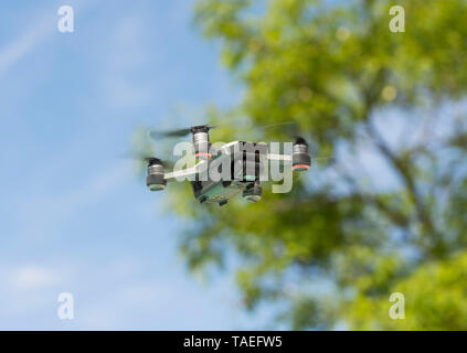 Drone copter, DJI Spark, flying with high resolution digital camera, hovering and passing trees. Stock Photo