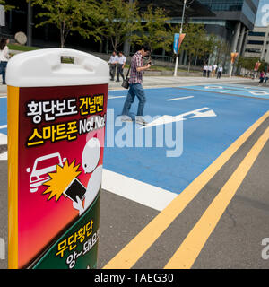 Close-up of warning road sign with man using mobile phone in the background, Suwon, South Korea Stock Photo