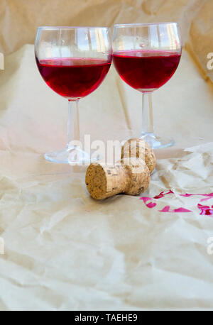 two glasses of red wine, champagne, cocktail on the background of old paper, near the cork of the champagne, female alcoholism, alcohol problem. Stock Photo