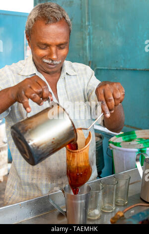 Vertical portrait of a man making traditional tea or chai in India. Stock Photo