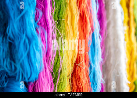 Horizontal close up view of multi coloured silk threads hanging in a workshop in India. Stock Photo
