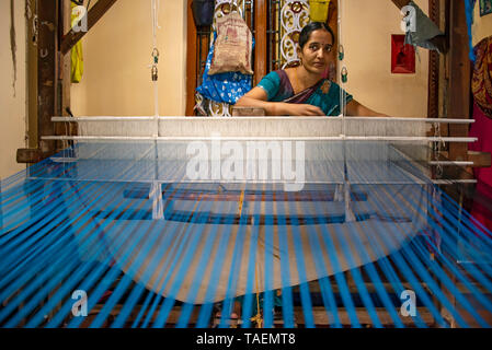 Horizontal portrait of a lady using a floor loom in India. Stock Photo