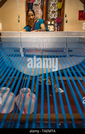 Vertical portrait of a lady working at a floor loom in India. Stock Photo