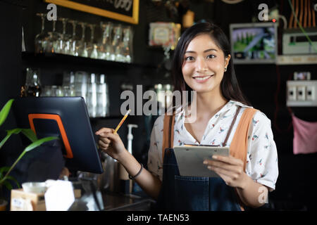 Asian women Barista smiling and using coffee machine in coffee shop counter - Working woman small business owner food and drink cafe concept Stock Photo