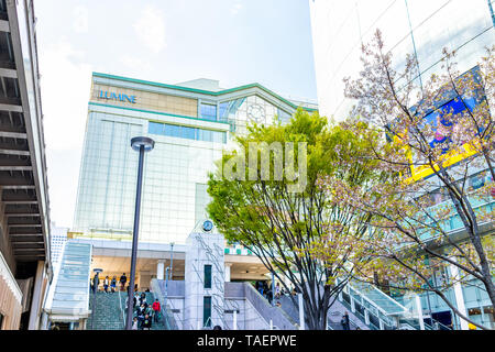 Tokyo, Japan - April 2, 2019: Shinjuku modern building station architecture during day with many people walking by retail stores shops Stock Photo