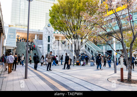 Tokyo, Japan - April 2, 2019: Shinjuku modern building station during day with many people walking by retail stores shops Stock Photo