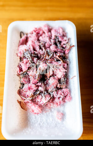 Traditional japanese storebought red pink salted sakura flower pickles flat top closeup on wooden table Stock Photo