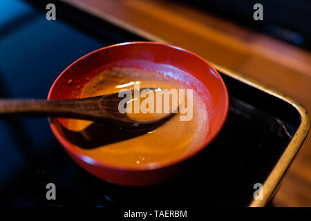 Traditional japanese bowl in restaurant with black lacquered wood table background and miso sauce and spoon Stock Photo