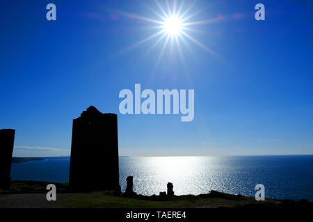 The tin mines of Wheal Coates silhouetted against a flared sun on the North Cornish coast, UK - John Gollop Stock Photo