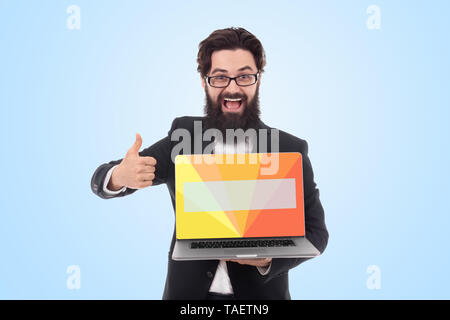 cheerful bearded businessman holding digital laptop with colorful screen for advertising and showing thumb up over blue background Stock Photo