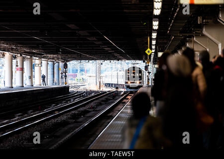 Utsunomiya, Japan - April 4, 2019: Train station platform local line to Nikko sign with many people waiting by tracks and incoming train Stock Photo