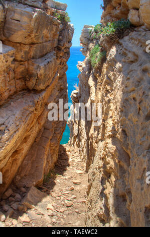 View through a narrow cave at the blue sea and sky Stock Photo