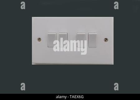 Four way electrical light switch.  White plastic switch with two screws and set against dark grey background. Stock Photo