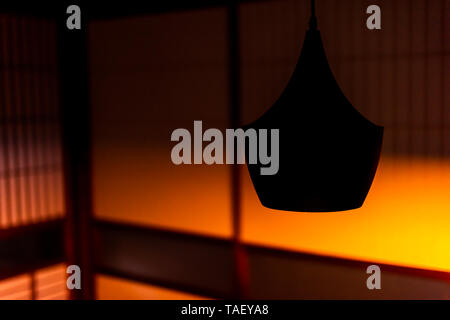 Traditional japanese machiya house or ryokan restaurant with hanging lamp and dark evening night background of shoji sliding paper door with orange li Stock Photo