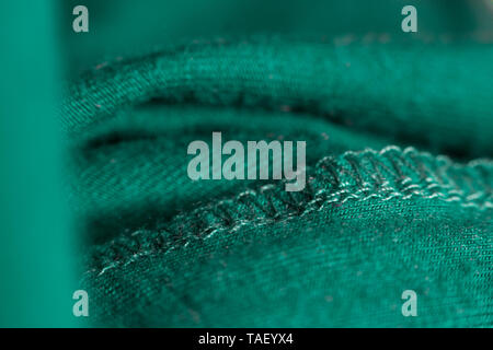 Close-up of the seam worked on the green fabric, the concept of tailoring, recycling things Stock Photo