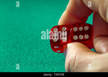 Closeup of hand holding red dice with a winning combination on green cloth in a casino, concept of winning Stock Photo