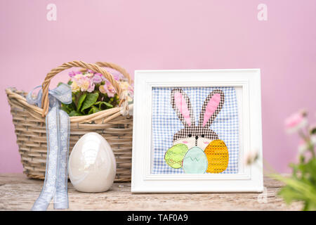 An Easter bunny and Easter eggs are applied on checkered fabric pattern. It is located in a white frame. Merry decoration for easter beside easter egg Stock Photo
