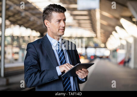 Businessman using tablet at train station Stock Photo