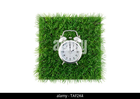Old style alarm clock on square of green grass field isolated on white background with clipping path Stock Photo
