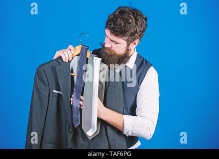 Shopping concept. Shop assistant or personal stylist service. Stylist advice. Matching necktie with outfit. Man bearded hipster hold neckties and formal suit. Guy choosing necktie. Perfect necktie. Stock Photo