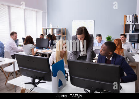 Young Female Manager Discussing With Her Multi-ethnic Colleagues In Office While Working Stock Photo