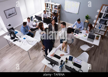 Group Of Businesspeople Discussing Together With His Colleague Working In The Office Stock Photo