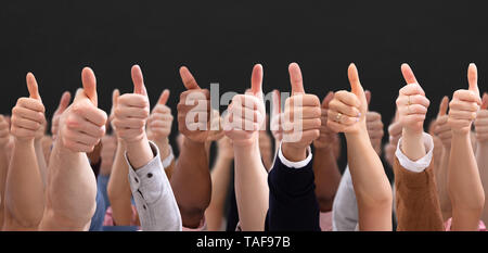 Close-up Of People's Hand Showing Thumb Up Sign Over Black Backdrop Stock Photo